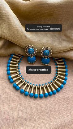 a necklace and earring set with blue beads on a beige cloth covered tablecloth