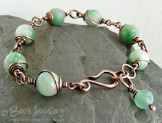 a bracelet with green beads and copper wire