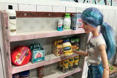 there is a doll that is standing in front of a shelf with food and drinks on it