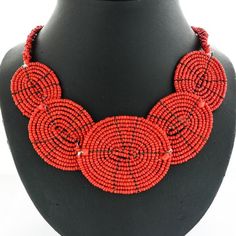 an orange beaded necklace is displayed on a mannequin neckpiece with red beads