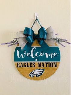 a wooden sign that says welcome to the eagles nation hanging on a wall with blue ribbon