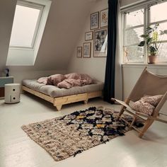 a room with a bed, chair and rug in it on the floor next to a window