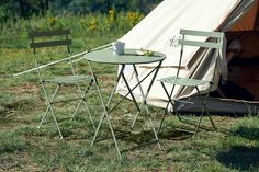 two chairs and a table in front of a tent