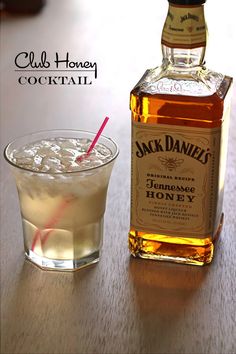 a bottle of jack daniels sitting next to a glass filled with ice and a straw