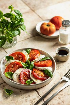 tomatoes and mozzarella in a bowl with basil on the side next to a fork