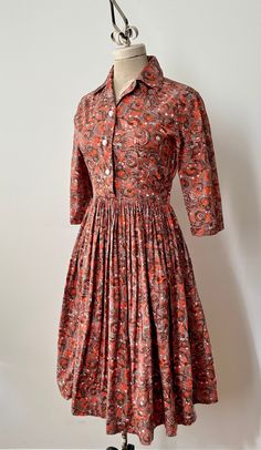 "A perfectly crisp and vibrant cotton babe from the late '40s/early '50s in a swirled print of orange, brown and white.  This shirtwaist dress features a functional button up bodice, side metal zipper, 3/4 length sleeves and a nice full pleat skirt.  In mint vintage condition with no flaws to note. Freshly laundered and ready to wear.  ~ Measurements ~  Bust: 36\" Waist: 28\"- 29\" very snug Hip: open Sleeve Length: 15\" Bodice Length: 15\" Skirt Length: 26\"" 1940s Housewife Fashion, Vintage Shirtwaist Dress, Vintage Collared Brown Dress, Vintage Brown Collared Dress, Fitted Orange Vintage Dress, Retro Brown Dresses For Daywear, Retro Brown Dress For Daywear, 40s Fashion 1940s Style, 1930s Outfits