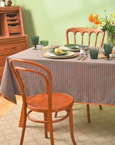 a dining room table set for two with plates and glasses on it, next to a dresser