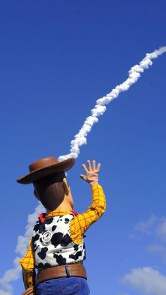 a man flying a kite in the sky with a cow suit on and hat on