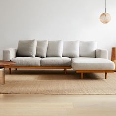 a white couch sitting on top of a wooden floor next to a table and lamp