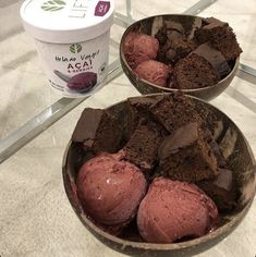 two bowls filled with ice cream and brownies on top of a glass table next to an ice cream container