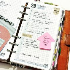 an open notebook with sticky notes on it and a pink house magnet attached to the cover