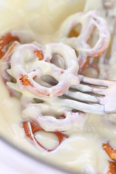 a close up of a fork in a bowl of food with cheese and sauce on it