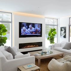 a living room filled with white furniture and a flat screen tv mounted to the wall