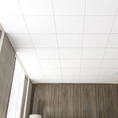 a bathroom with wood paneled walls and white ceiling tiles on the wall, along with two urinals