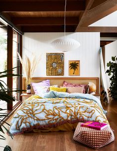 a bedroom with wood flooring and white walls, has a large bed covered in colorful comforter