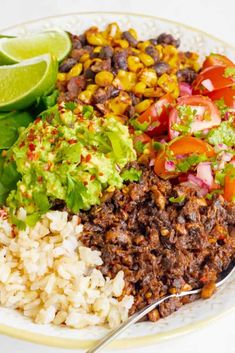 a white plate topped with rice, meat and veggies next to a lime wedge