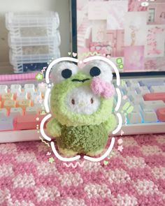 a small stuffed animal sitting on top of a pink and white blanket next to a computer keyboard