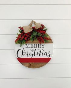 a merry christmas sign hanging on the side of a white wall with red and green decorations