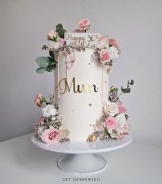 a birthday cake decorated with flowers and greenery