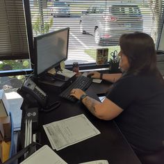 a woman sitting at a desk in front of a computer monitor, keyboard and mouse