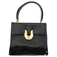 Stylish black patent leather adjustable handbag made by high end manufacturer, Koret. This bag has a fold over flap with an unusual brass U-shaped twist clasp closure. The interior is lined with leather and has a pocket with a chain purse tethered by a slender chain. This versatile bag has a strap that can be adjusted so that it can also be used as a shoulder bag. Marked with Koret logo on the inside. Koret was a leading designer and manufacturer of bags in the 40's and 50's, and examples are in Elegant Black Shoulder Bag With Glossy Finish, Elegant Formal Shoulder Bag With Glossy Finish, Elegant Glossy Finish Shoulder Bag For Formal Use, Elegant Glossy Finish Shoulder Bag For Formal Occasions, Elegant Black Glossy Shoulder Bag, Elegant Rectangular Bag With Glossy Finish, Elegant Shoulder Bag With Glossy Finish For Office, Elegant Formal Satchel With Fold Over Clasp, Elegant Evening Shoulder Bag With Glossy Finish