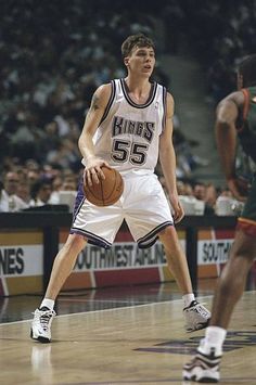 a basketball player dribbles the ball during a game in front of an audience