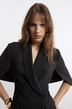 a woman in a black suit posing with her hands on her hips