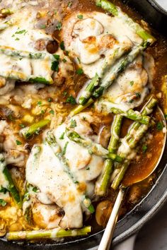 a skillet filled with chicken and asparagus covered in gravy