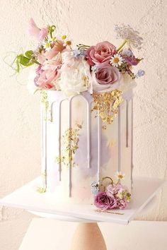 a cake decorated with flowers and icing on top of a white table next to a wall