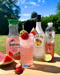 some drinks are sitting on a table with watermelon, lemon and strawberries