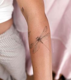 a woman's arm with a dragonfly tattoo on it