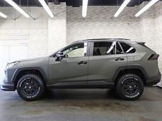 a gray jeep parked in a garage next to a white brick wall with lights on