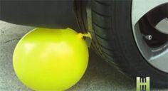 a yellow ball sitting on the ground next to a black tire and a white car