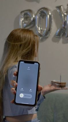 a woman holding up her cell phone in front of a wall with the words yahoo on it