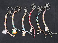 four key chains with charms attached to them on a black cloth covered surface, one has an elephant and the other is a dog