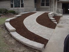 a driveway with steps leading up to the front door and landscaping area on either side