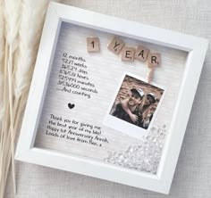 a photo frame with the words 1 year written on it next to some dried grass