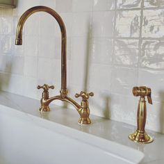 two brass faucets on a white sink in a bathroom