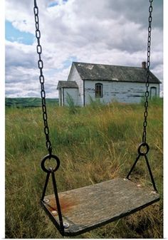 an old abandoned house sitting in the middle of a field with a swing on it