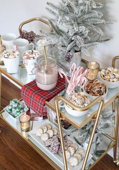 a christmas dessert bar with candy, candies and other treats on a gold serving cart