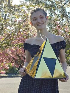 a woman in a dress is holding a bag with a triangle on it and smiling