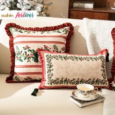 two pillows on a couch with coffee cup and saucer in front of the pillow