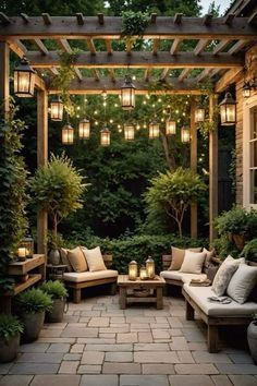 an outdoor seating area is lit up with lanterns and potted plants on either side