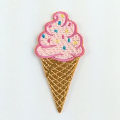 a pink ice cream cone with sprinkles on it's tip is embroidered onto a white surface