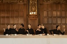 five women sitting at a long table with cups and saucers in front of them