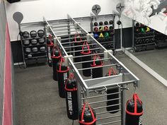 a gym with punching bags and boxing gloves on the rack, in front of a mirror