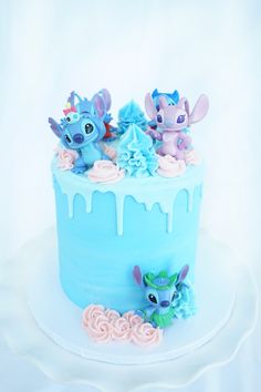 there is a blue frosted cake decorated with littlest petunis on top