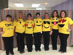 a group of women in yellow shirts standing next to each other wearing emoticive t - shirts