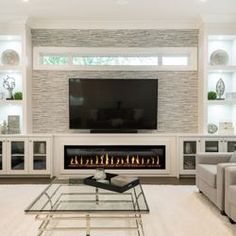 a living room with couches and a television mounted on the wall over a fireplace