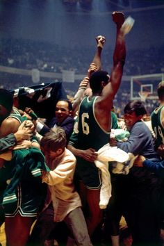 a group of men standing next to each other on top of a basketball court in front of a crowd